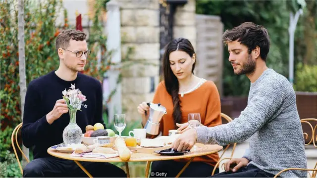 Dois homens e uma mulher tomam café