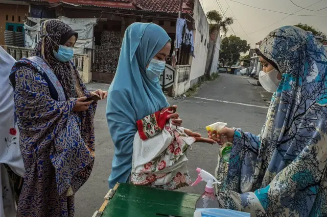 A woman sprays hand sanitizer before Eid al-Fitr prayers in Yogyakarta, Indonesia