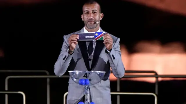 L'ancien attaquant marocain Mustapha Hadji montre le bulletin de vote de la Namibie lors de la cérémonie de tirage au sort de la CAN 2019.