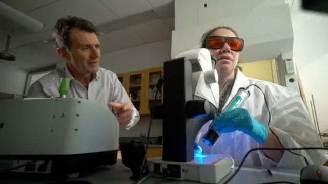 प्रोफ़ेसर मेसन (दाएं) डेविड शुकमैन को परिणाम दिखाते हुए