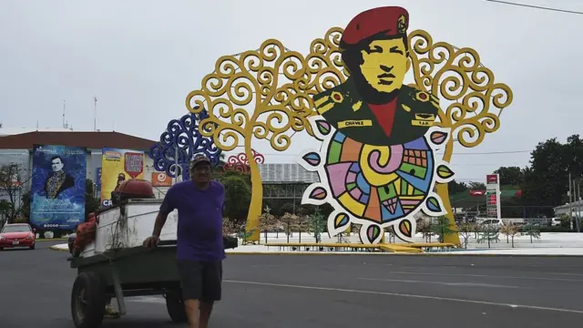 Un hombre con un carretón pasa cerca del monumento a Chávez en Managua