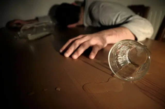 A man collapsed near an empty glass