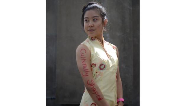 Stephanie wearing a Chinese dress with the words 'culturally shaped' written down the side of her arm.