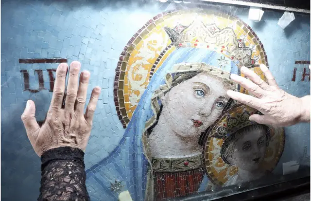 People touch a depiction of the Virgin Mary after a mass at Cairo's Historical Church of Blessed Virgin Mary.