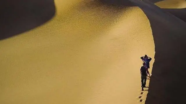 شخصان يسيران على الكثبان الرملية