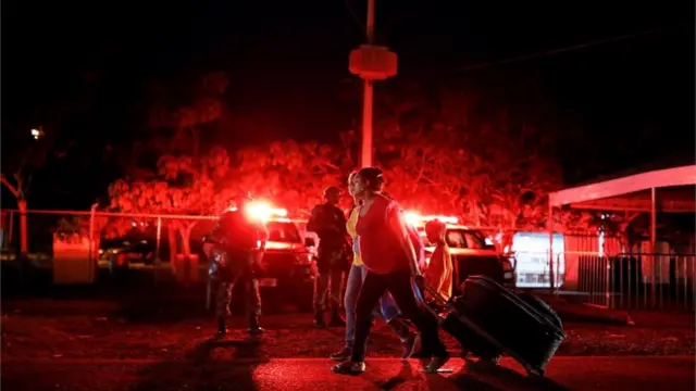 Personas cruzan la frontera entre Venezuela y Brasil.