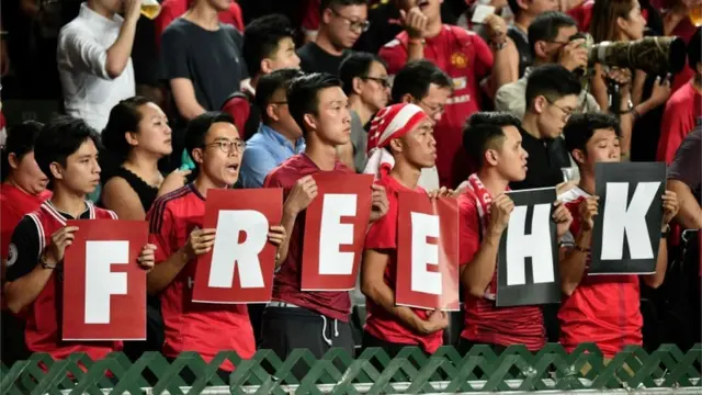 People in the stands hold up placards reading "Free HK" in reference to the recent protests in the city, at the start of the Qatar 2022 World Cup qualifying football match between Iran and Hong Kong at Hong Kong Stadium on September 10, 2019.