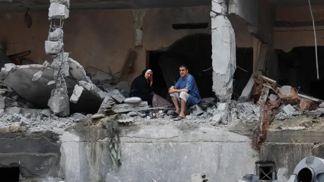 兩位巴勒斯坦人坐在加沙一處被炸住宅樓廢墟內（10/10/2023）