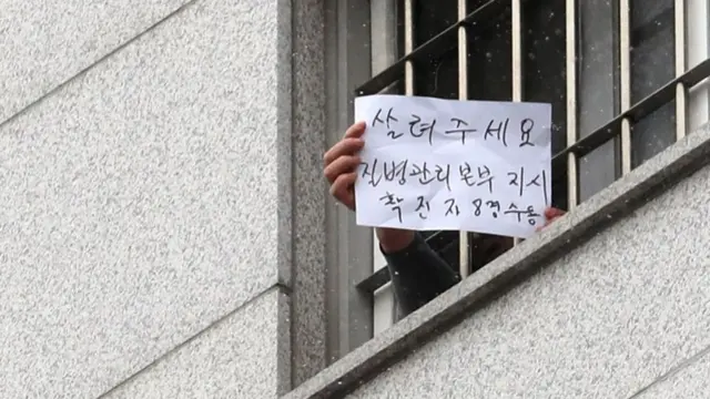 29일 서울 송파구 동부구치소에서 한 수용자가 자필로 '살려주세요'라고 쓴 문구를 취재진에게 보여주고 있다