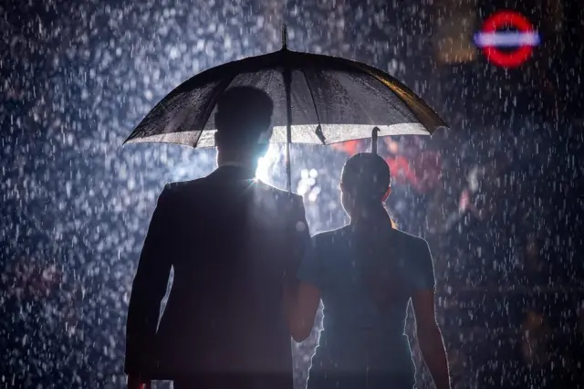 принц Гарри и Меган под зонтиком, вид со спины