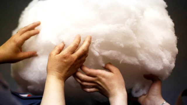 Manos tocando una nebulosa de un material parecido al algodón.