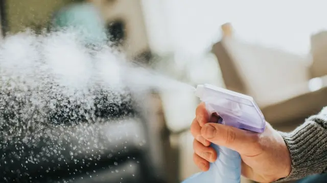 Une main appuie sur le diffuseur d'un produit de nettoyage.