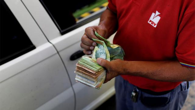 Persona cuenta billetes en una estación de servicio de PDVSA