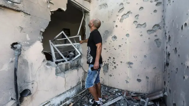 A man looks at rocket damage to his home in Sderot, Israel, 20 May