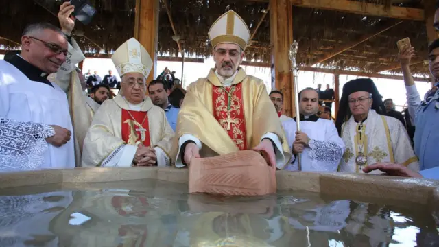 المطران بيير باتيستا بيتسابالا يبارك الحجاج بمياه وادي الأردن خلال القداس في كنيسة العمادة