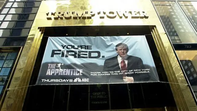 پرچمی با نشان برنامه تلویزیونی 'کارآموز' بیرون برج ترامپ، پیش از پخش اولین قسمت برنامه