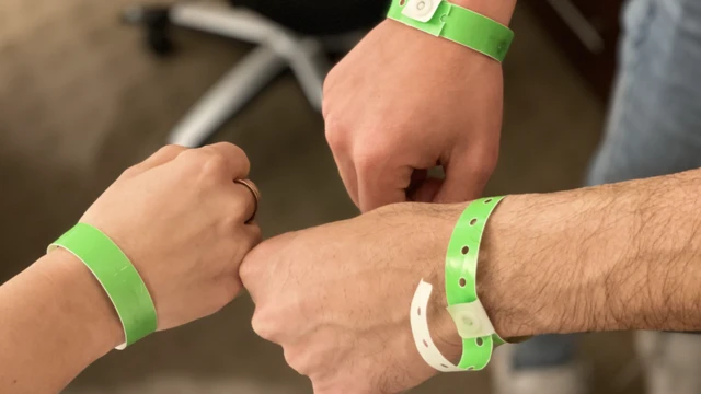 Tres manos de refugiados con manillas con las que pueden reclamar cada comida en los albergues.