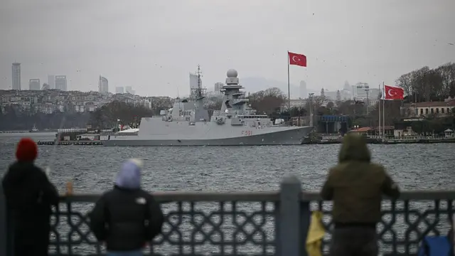 İstanbul'da Haliç üzerinde bir köprüde önce balık tutan insanlar, arkada İtalyan donanma gemisi