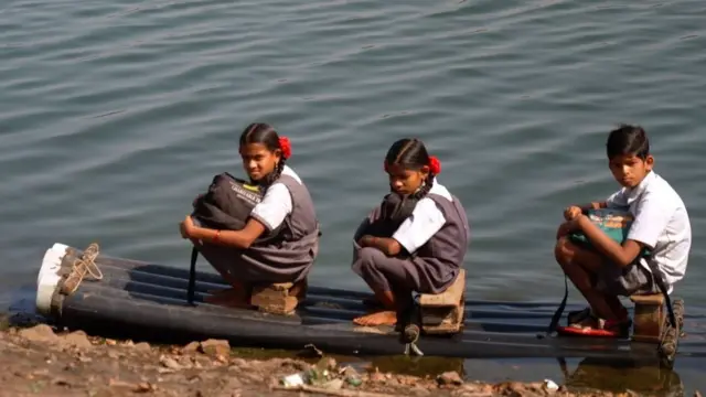 प्लॅस्टिकच्या पाईपने बनवलेल्या तराफ्यावर बसून विद्यार्थी पाऊण तास प्रवास करतात.