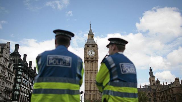 ضابطا شرطة بريطانيا يقفان قرب مقر البرلمان التي يظهر برج ساعته الشهر.