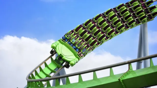 People siting in the front row of green rollercoaster as it turns a bend