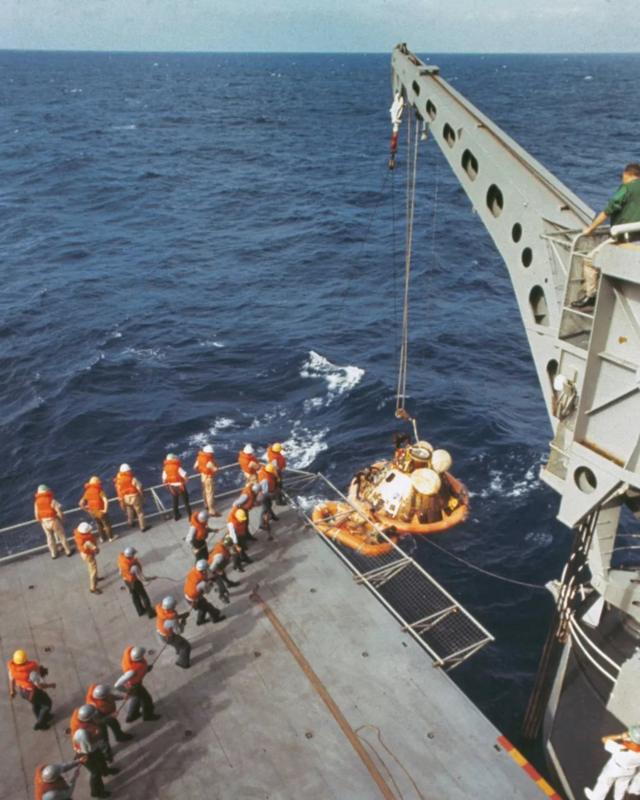 一架起重機將阿波羅11號太空艙抬到飛船上，而宇航員已經在飛船上了。