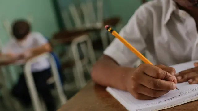 Un niño escribiendo en su pupitre