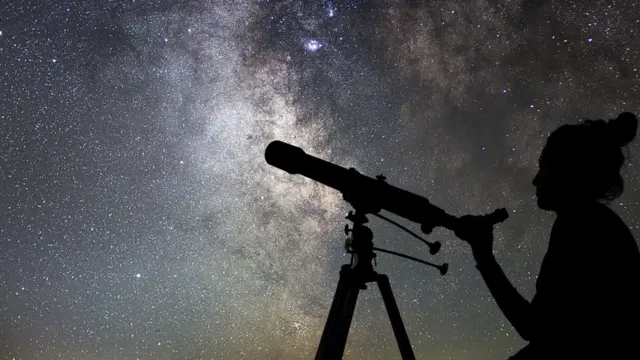 Imagem mostra pessoa apontando telescópio para as estrelas