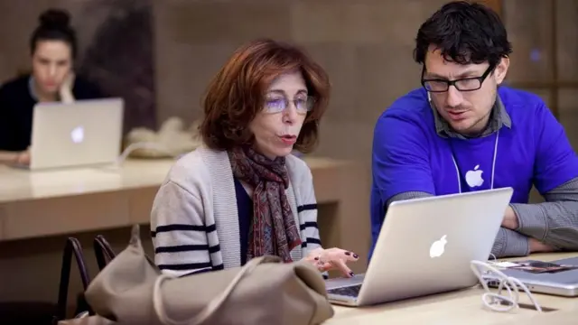 موظف وموظفة ينظران إلى شاشة كمبيوتر محمول