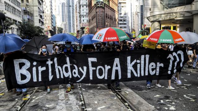 有示威者举起写上"杀人犯的生日？"的横幅。