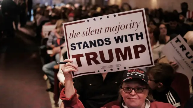 Una mujer sostiene un cartel con la leyenda "la mayoría silenciosa está con Trump".