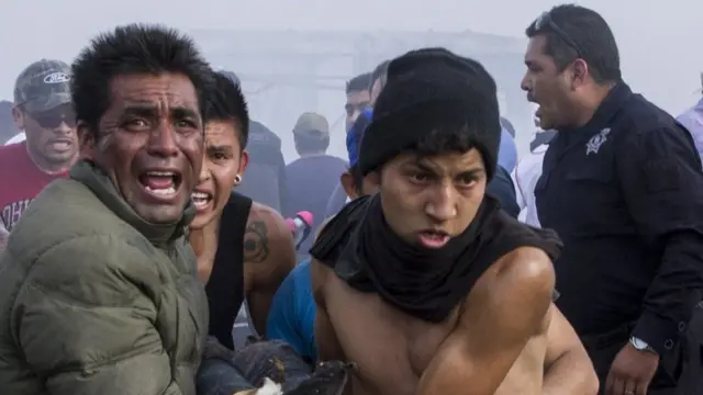Hombres ayudan a heridos de la explosión en Tultepec