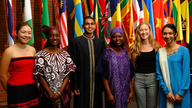 Estudiantes de Berea College parados frentes a banderas de varios países.