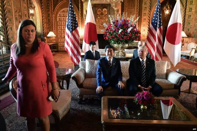 US President Donald Trump greets Japanese Prime Minister Shinzo Abe as he arrives for talks at Trump"s Mar-a-Lago resort in Palm Beach, Florida, on 17 April 2018. White House Press Secretary Sarah Sanders is at left