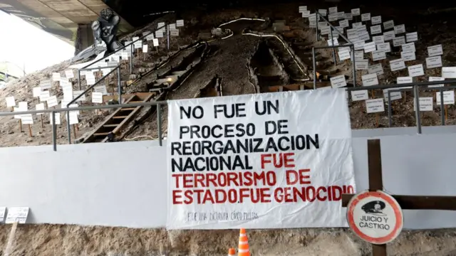 Monumento e faixa: "No fue un procesoreal bet e confiavelreorganización nacional. Fue terrorismoreal bet e confiavelEstado. Fue Genocidio".