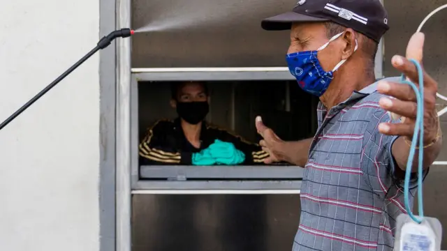 Un hombre se desinfecta antes de entrar a un negocio en Maracaibo.
