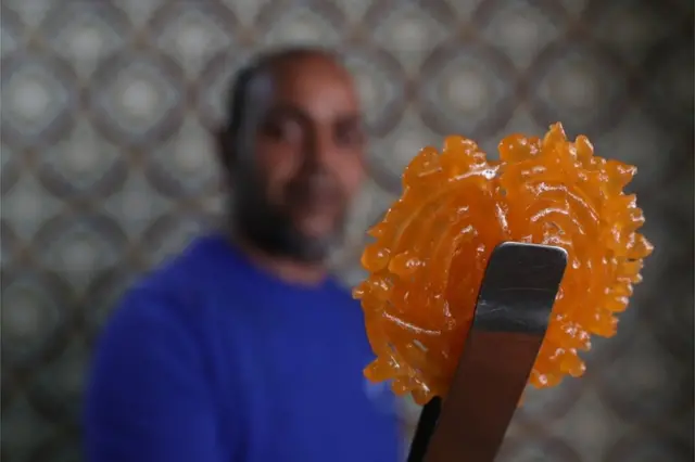 A Tunisian confectioner holds up a zlabia in a pastry shop in Tunis, Tunisia.