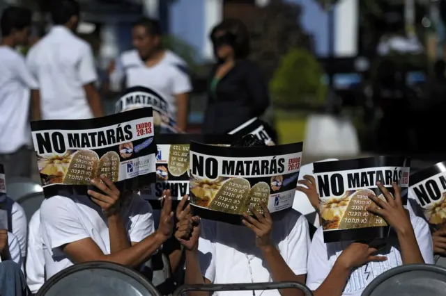 Pandilleros se cubren la cara con unos documentos en los que se lee "No matarás" durante un servicio religioso en Apopa, 14 kilómetros al norte de San Salvador, El Salvador, el 4 de enero de 2013.