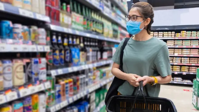 Mulher comprando cervejanovibet iphoneum supermercado