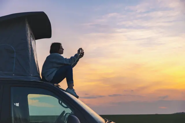 Una mjer sentada sobre un auto