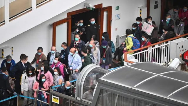 Passengers queue up to finally disembark from the World Dream cruise ship