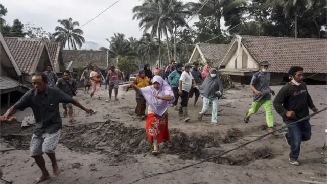 Orang-orang memeriksa desa mereka yang telah terkubur oleh abu vulkanik di kawasan Gunung Semeru, Jawa Timur.