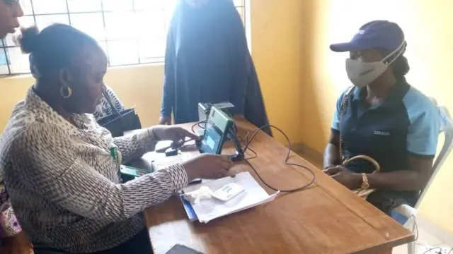 Awọn oṣiṣẹ ajọ INEC n ṣe iforusikọlẹ oludibo kan.