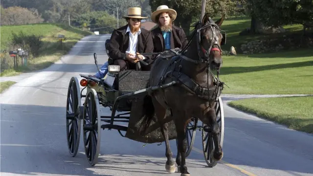 Dos amish se trasladan en una carreta.