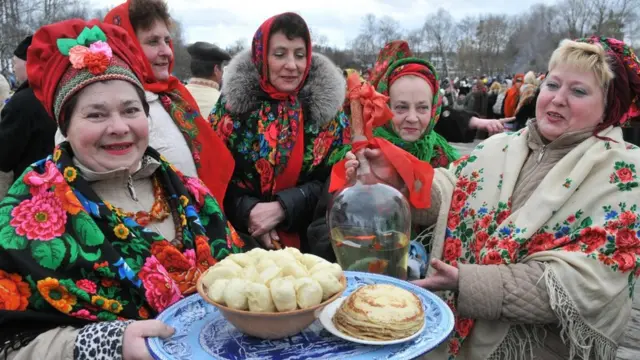 Жінки в народних костюмах з варениками та млинцями