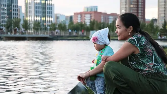 Қозоғистонлик ёш она фарзанди билан сўв бўйида