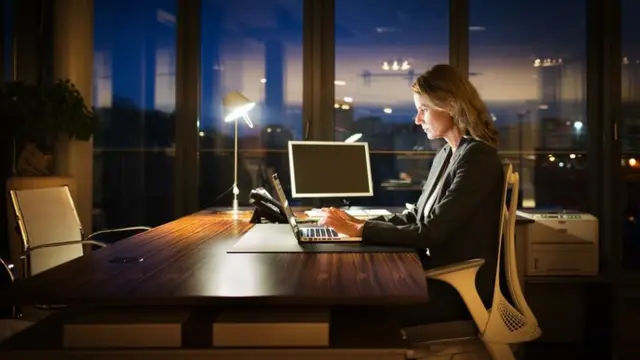 Una mujer trabajando de noche en una oficina solitaria