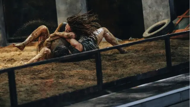 Two female contestants wrestle fiercely to steal a ball from each other