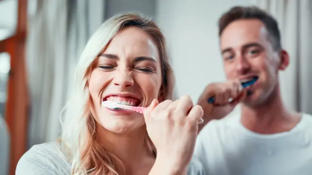 Pareja lavándose los dientes.