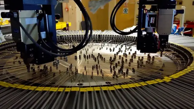 Jari-jari robot Weave yang gesit memposisikan seribu serat optik dengan tepat, masing-masing menunjuk ke sebuah bintang